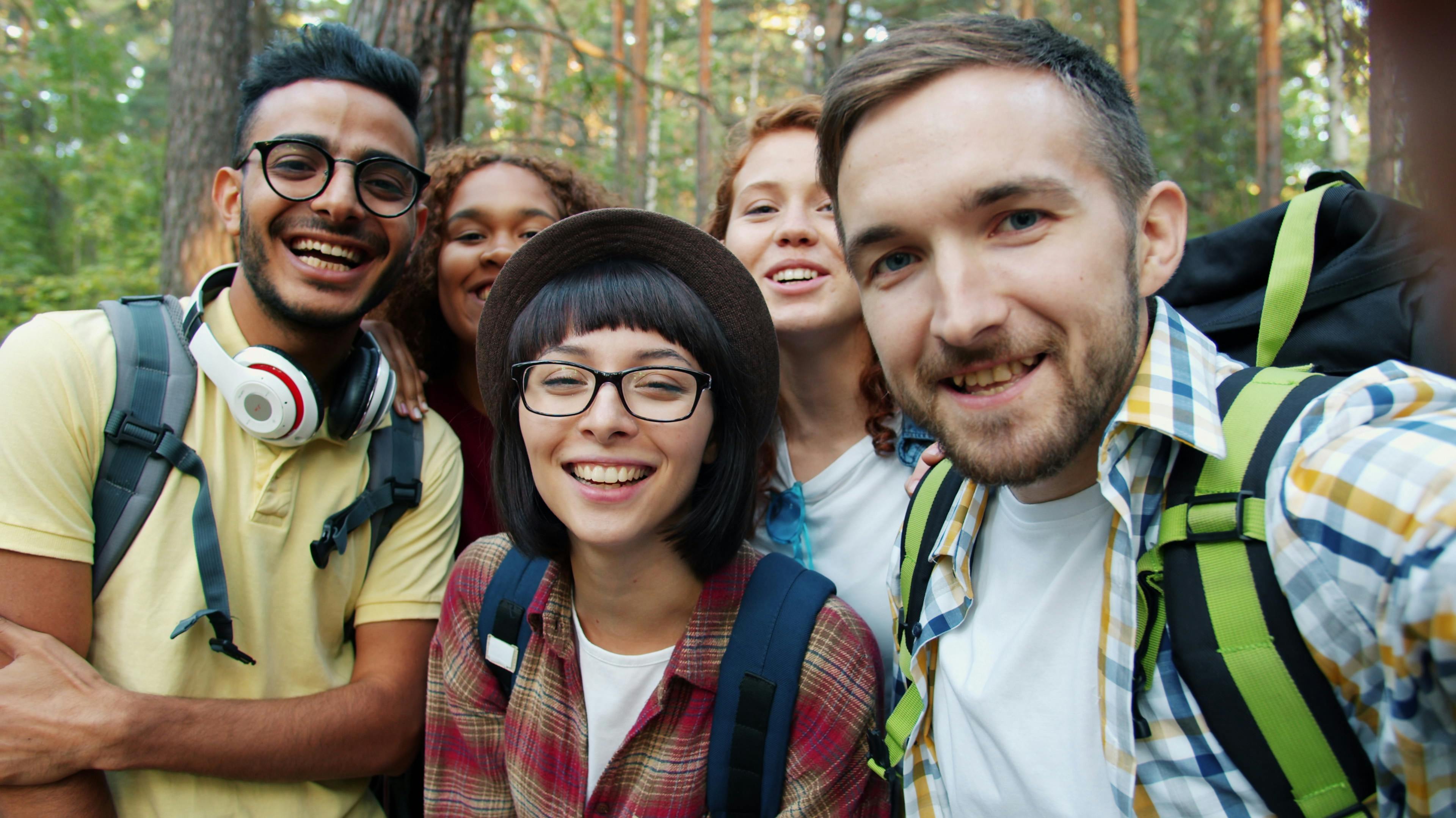 Happy friends taking a selfie during a forest hike, enjoying nature and companionship.